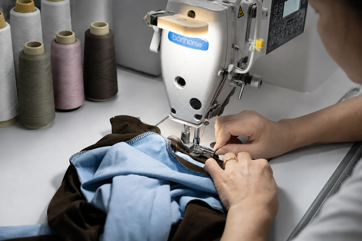 About Vanty Garment — Women’s Apparel Manufacturer Close-up of garment assembly on an industrial sewing machine
